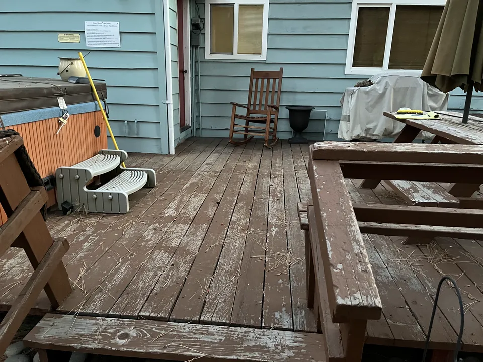 Weathered gray deck around a hot tub, photographed before restoration work.
