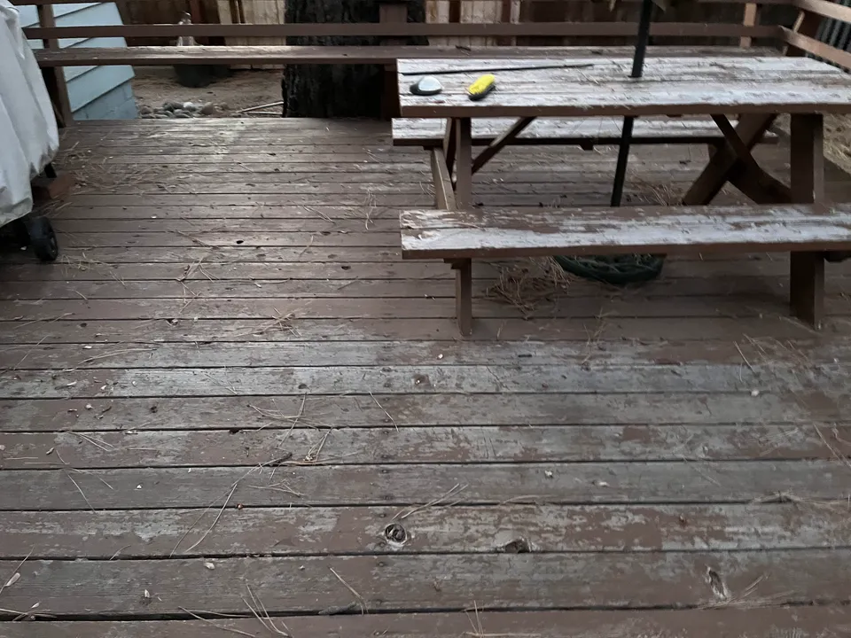 Before: the same style of deck weathered to bare silver-gray with the grain raised and splitting.