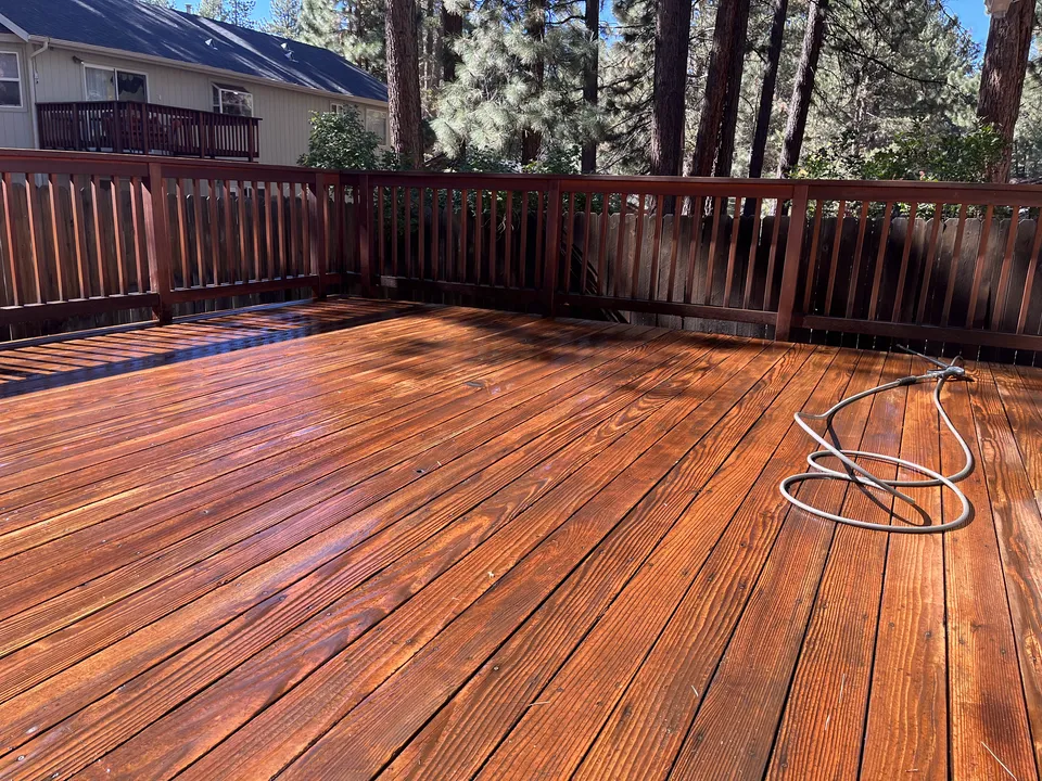 After: a redwood deck sanded and re-stained to a warm honey tone, railings sharp and even.