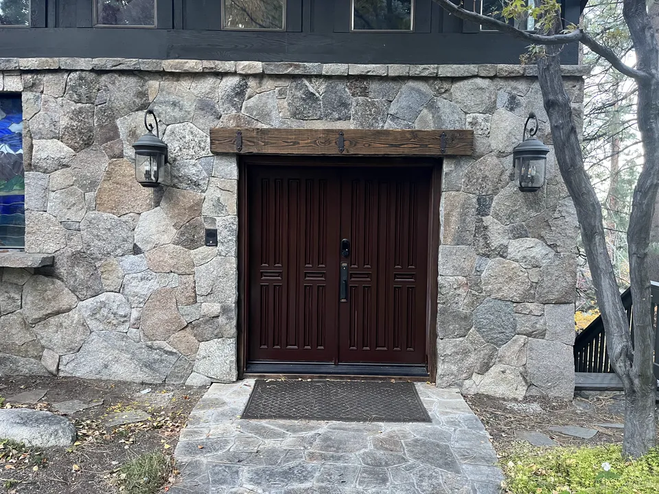 Stone-framed house entry with a deep, freshly finished dark front door.