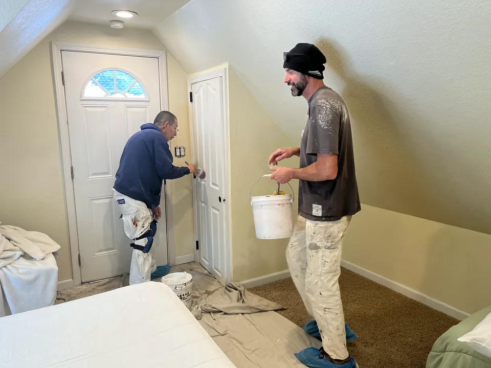 Painter carefully finishing an interior door and its casing with a brush.